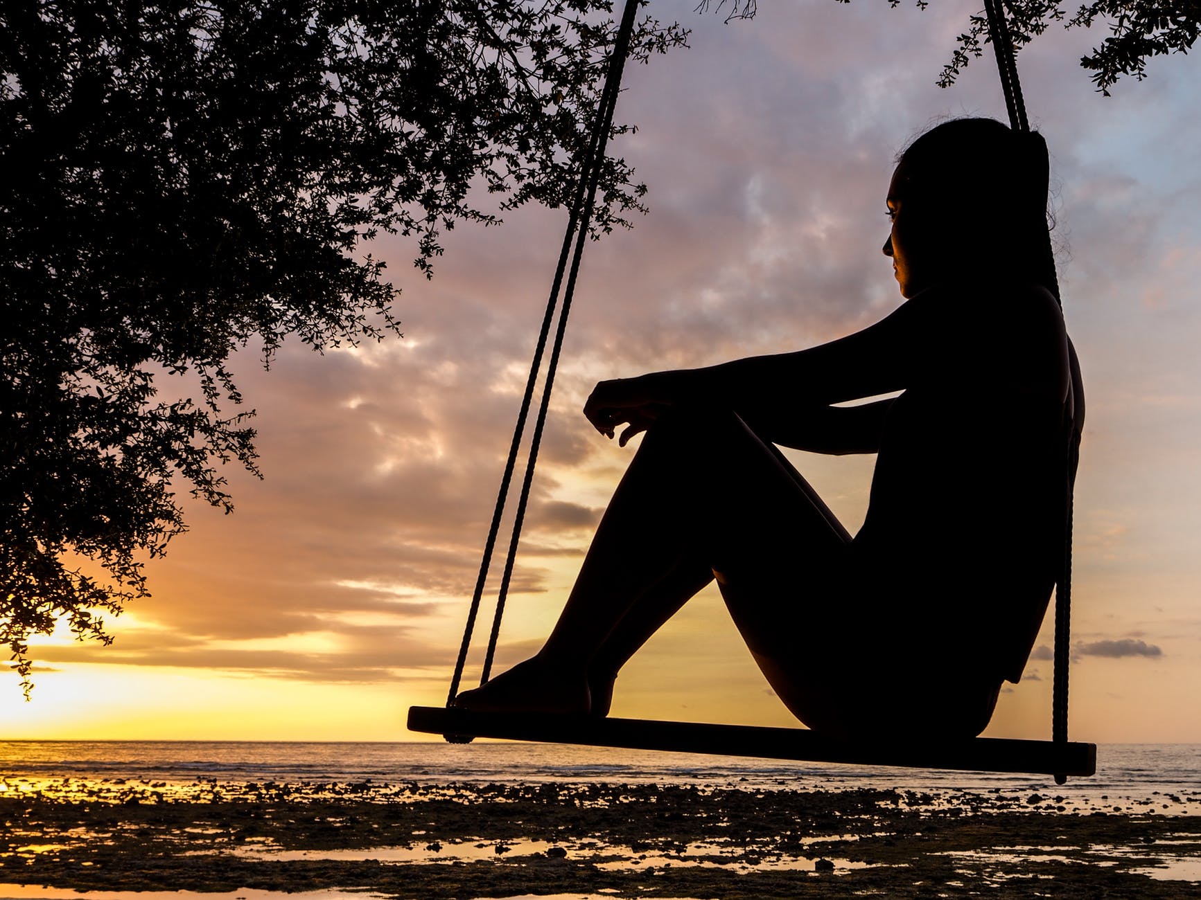 A lady sitting on swing looking at the horizon. It signifies deep thought.